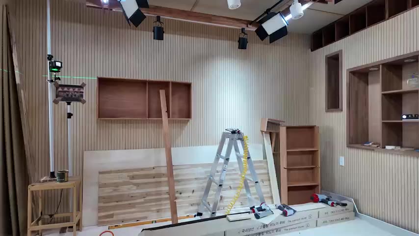 원목 루버 벽과 트랙 조명이 설치된 제작 중인 촬영 스튜디오 내부
